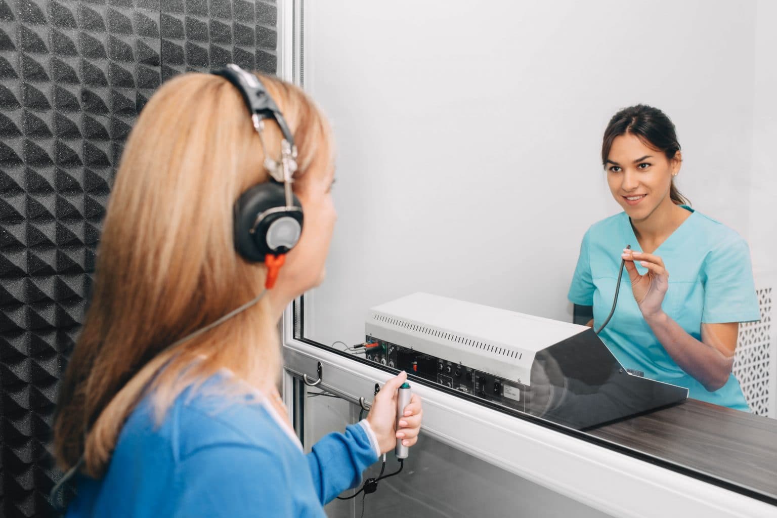 audiology patient completing hearing test Female audiologist performing a hearing test for a female patient