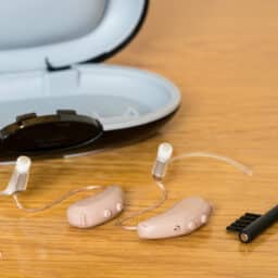 Hearing aids and a hearing aid case on a table.
