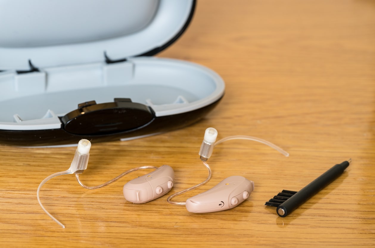 Hearing aids and a hearing aid case on a table.
