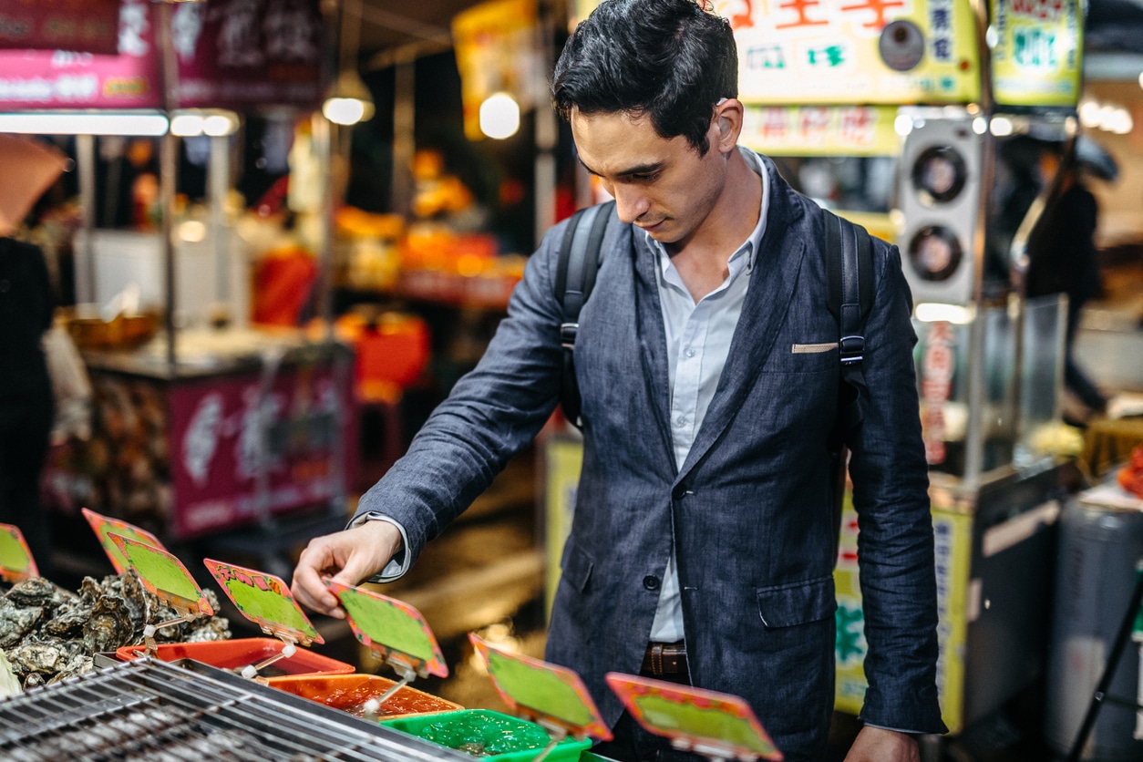 younger man in market looking at electronics - has visible hearing aid in ear