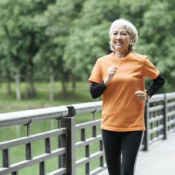 Woman jogging across a scenic bridge in a park, staying in shape for the new year.