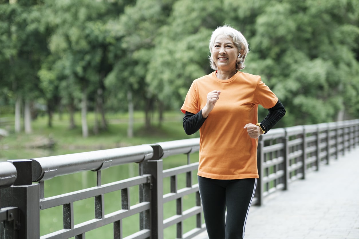Woman jogging across a scenic bridge in a park, staying in shape for the new year.