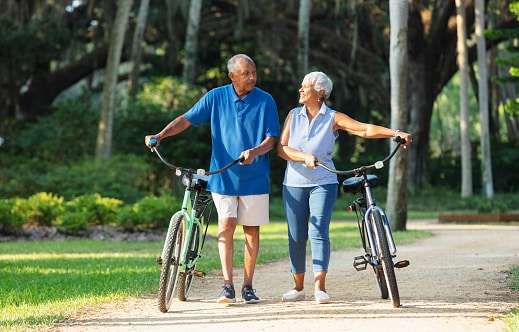 Happy couple walk their bikes together in a lovely wooded park.