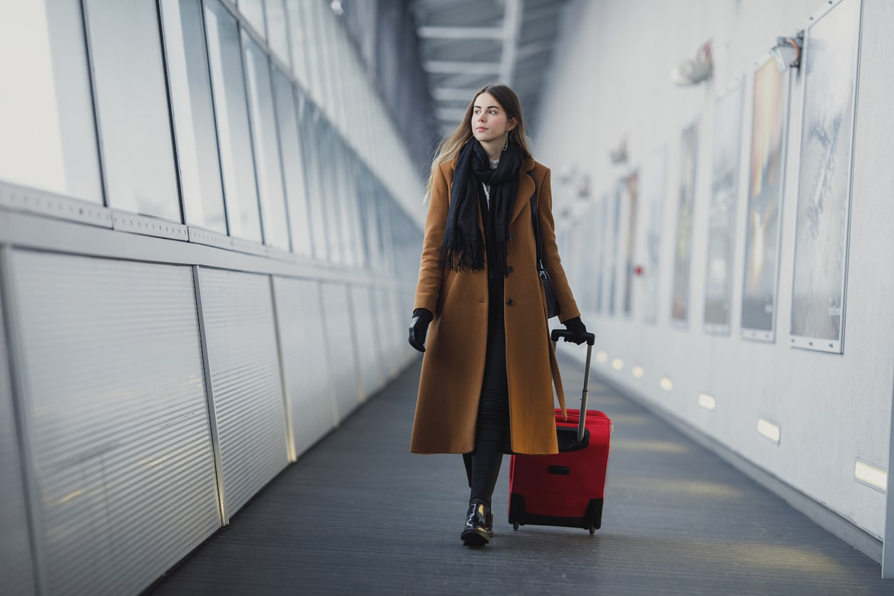 Woman pulling a red suitcase through the airport.