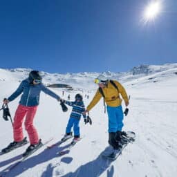 Family having fun snow skiing on a mountain on a sunny, cloudless day.