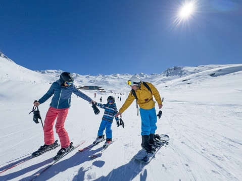 Family having fun snow skiing on a mountain on a sunny, cloudless day.