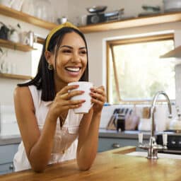 Happy woman with tinnitus looking comfortable at home, in a stylish kitchen with a cup of tea.