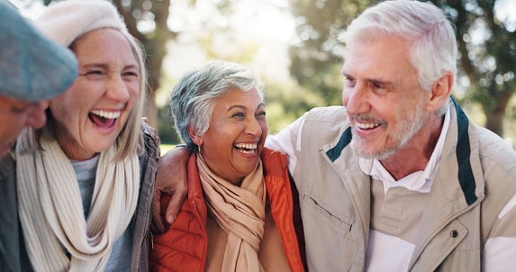 Happy group of friends laughing and hugging outdoors.