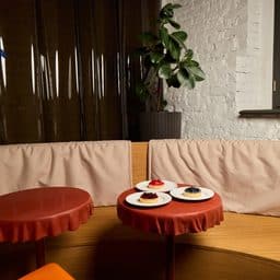 An inviting cafe setting that features beautiful dessert plates, vibrant seating options, and plenty of greenery